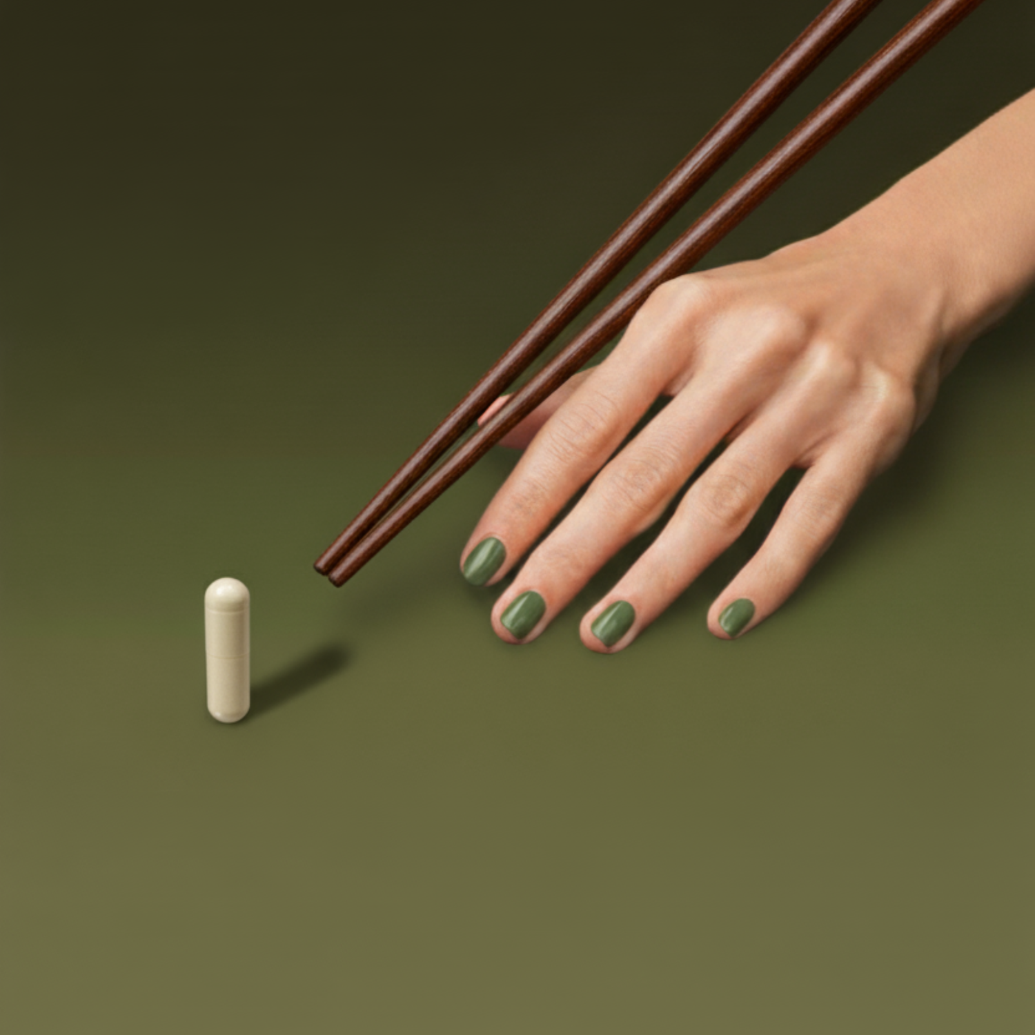 A hand with green nail polish, resting on a green gradient pool table surface. Brown chopsticks are being used as the pool stick is being aimed at a single pill standing vertically. 
