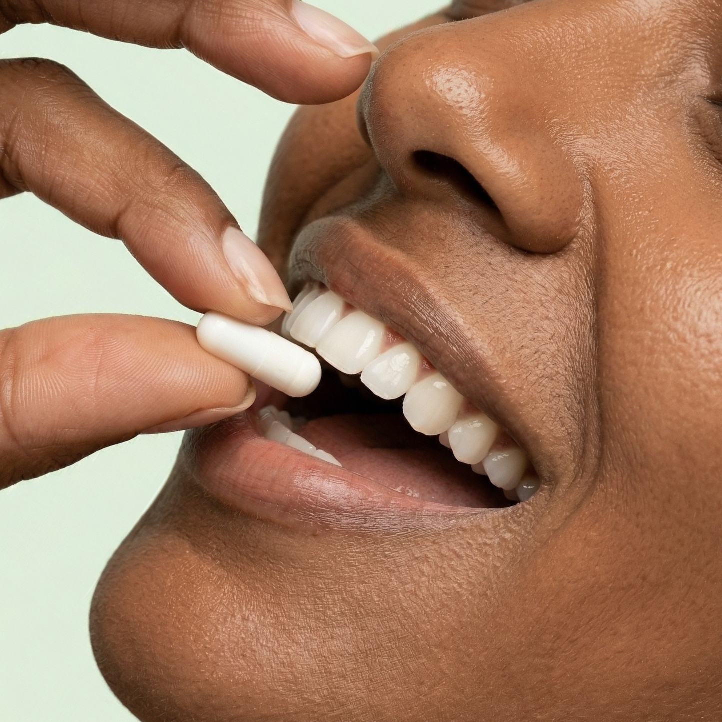 Person taking a pill with a neutral background