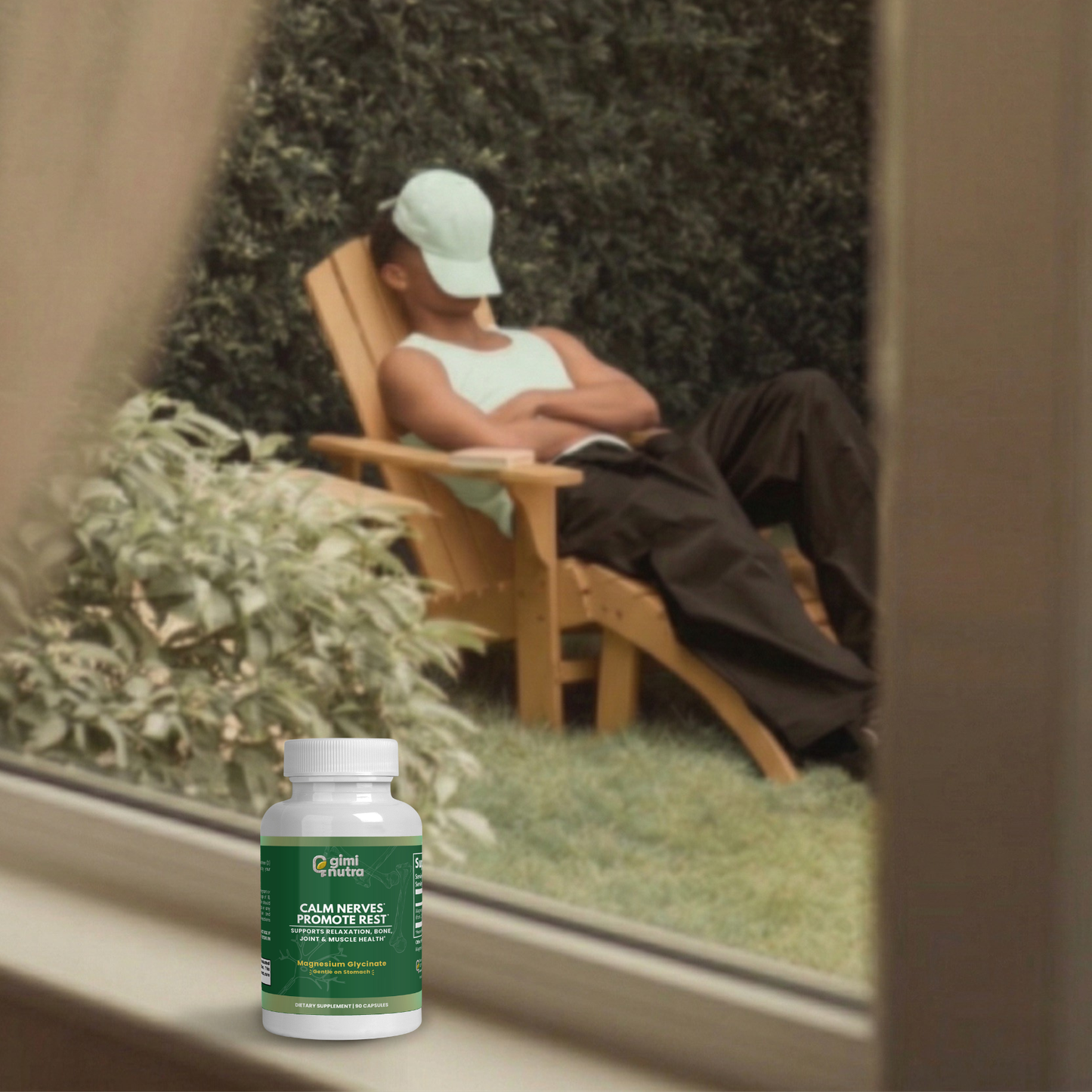 A man is shown relaxing in a chair in a serene outdoor scene through a window. On the ledge of the window, a bottle of giminutra magnesium glycinate bottle.