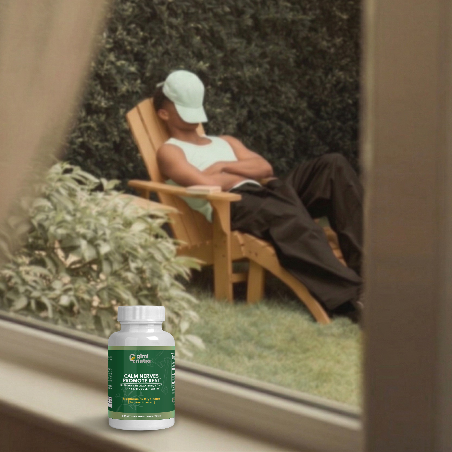 A man is shown relaxing in a chair in a serene outdoor scene through a window. On the ledge of the window, a bottle of giminutra magnesium glycinate bottle.