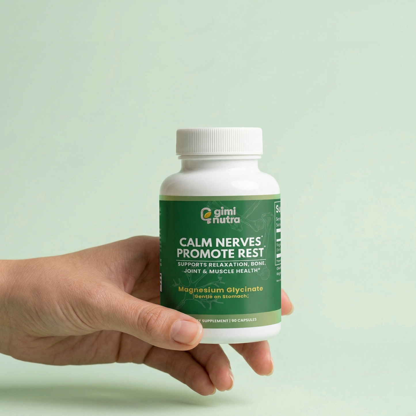 Hand holding a bottle of giminutra's magnesium glycinate with a green label on a light green background